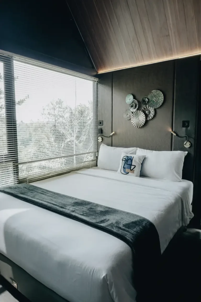 Ranjang king size minimalis dengan pemandangan hutan dari jendela kaca besar di Solitude Cabin