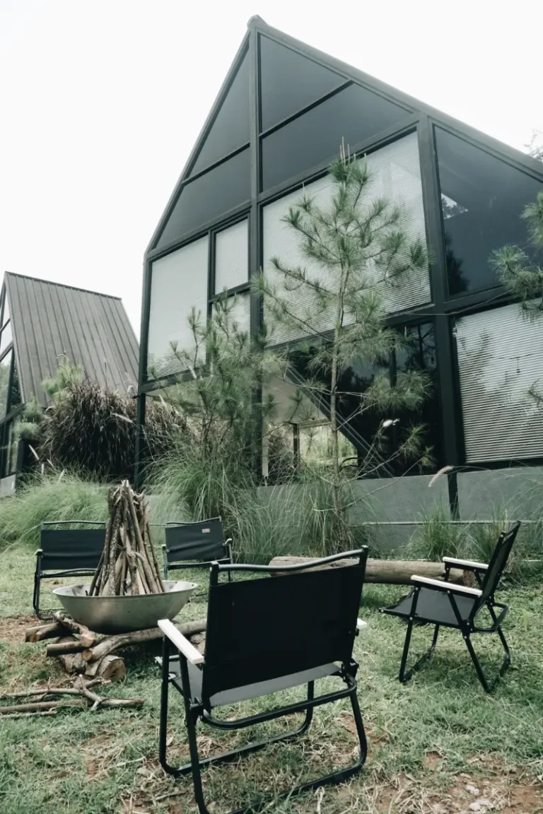 Desain eksterior cabin kaca modern A-frame dengan area api unggun di Solitude Villa