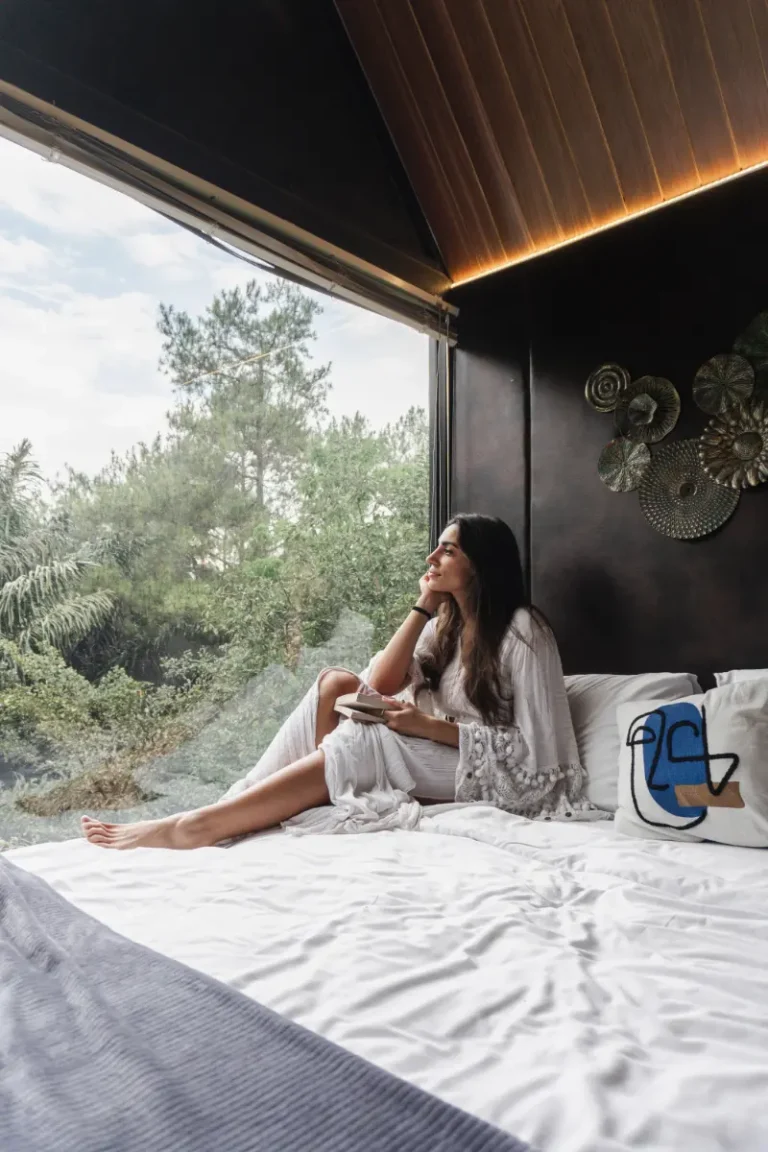 Wanita menikmati pemandangan hutan pinus dari dalam kamar tidur Solitude Cabin